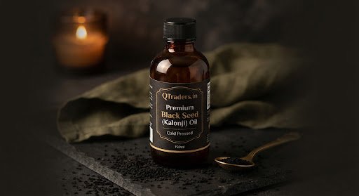 An amber glass bottle of cold pressed black seed kalonji oil with rich dark seeds around it in low warm lighting.