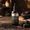 Dark amber bottle of cold-pressed Kalonji black seed oil with scattered nigella sativa seeds and whole dry dates in the foreground, medicinal aesthetic with warm lighting.