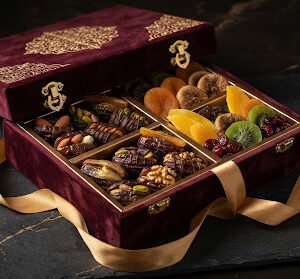 Extravagant royal velvet gift box opened with compartments filled with stuffed dates and exotic dried fruit treats tied with golden silk ribbon.