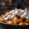 Macro photo showing genuine chandi ka varq silver foil floating over viscous honey and roasted cashew nuts in home kitchen.