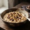 Wholesome organic talbina barley powder mixed with crushed dates and nuts in an antique ceramic serving bowl with natural morning lighting.